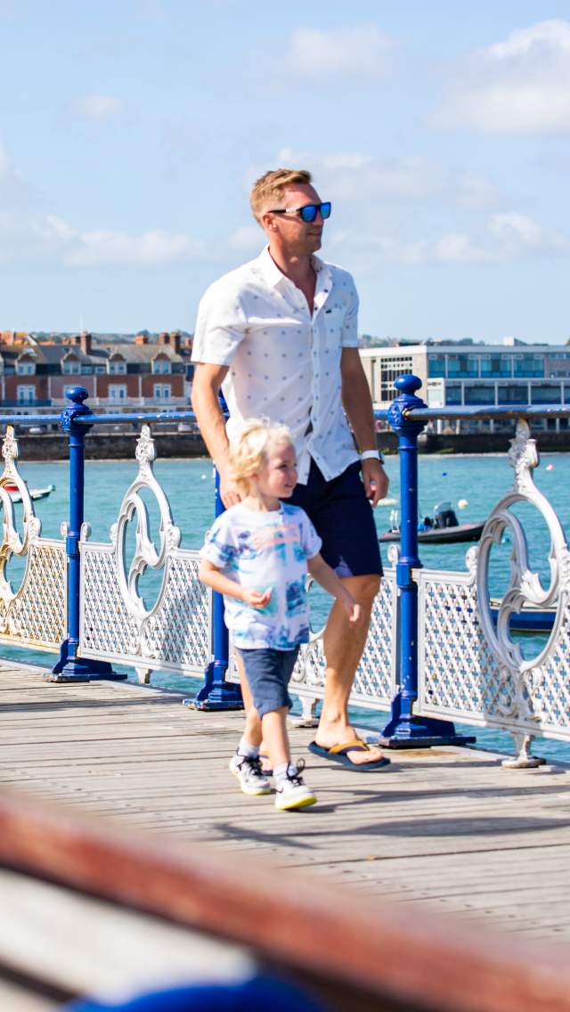 A family walking along Swanage Pier during the summer