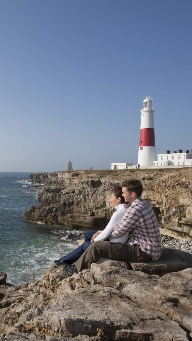 Man and woman sitting on the rocks at Portland Bill, Dorset