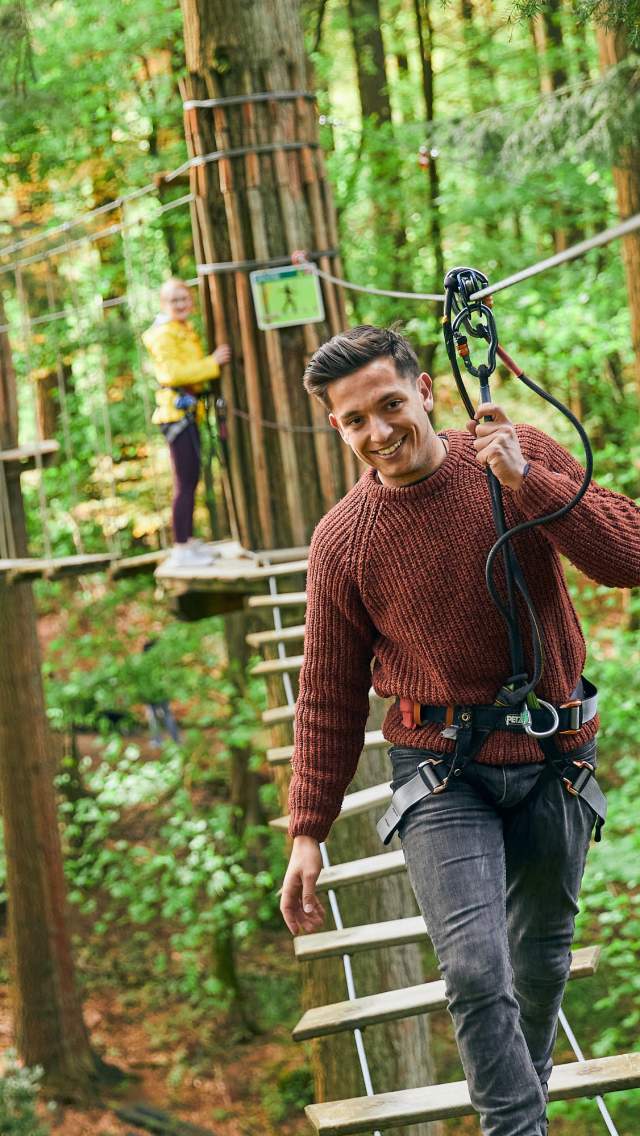Man crossing the tree top bridge at Go Ape, Moors Valley Country Park