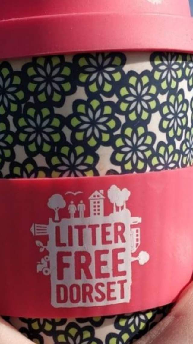 A person holding a Litter Free Dorset reusable coffee cup