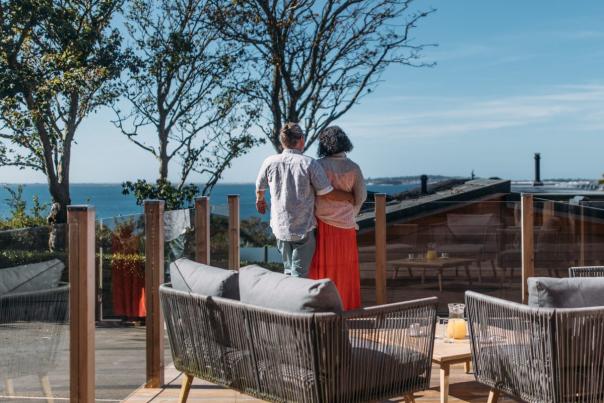 A man and woman looking towards the sea outside on a terrace at a luxury lodge park in Dorset