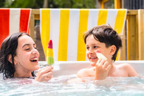 Two children sitting in a hot tub eating ice-lollies at Burnbake Forest Lodges in Dorset