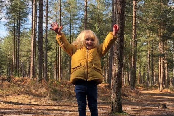 Child standing with their hands in the air in a forest in Dorset