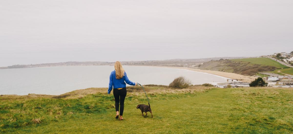 A woman walking a dog on the South West Coast Path near Bowleaze Cove in Dorset