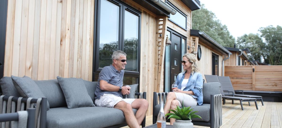 A couple sitting on the outside decking at one of the lodges at Bowleaze Cove Holiday Park & Spa in Dorset
