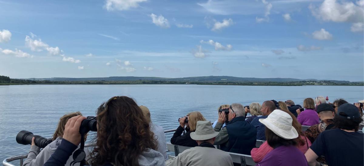 Birdwatchers on an Osprey Cruise in Poole Harbour looking through binoculars