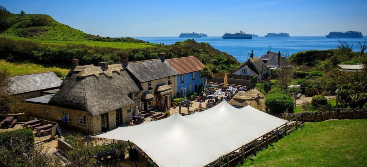 The Smugglers Inn pub at Osmington Mills in Dorset with views of the Jurassic Coast and cruiseships in the distance