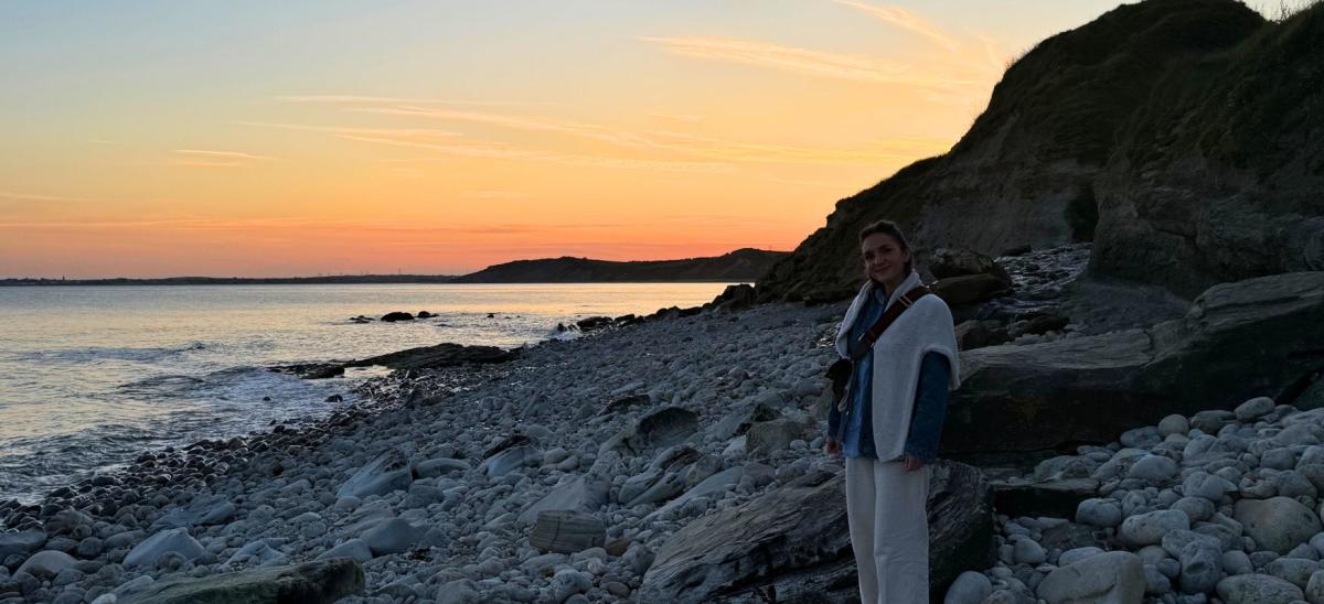 A woman standing on the Jurassic Coast near Osmington Mills in Dorset at sunset