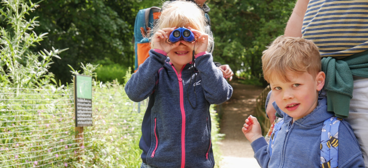 Two young children, girl holding up binoculars