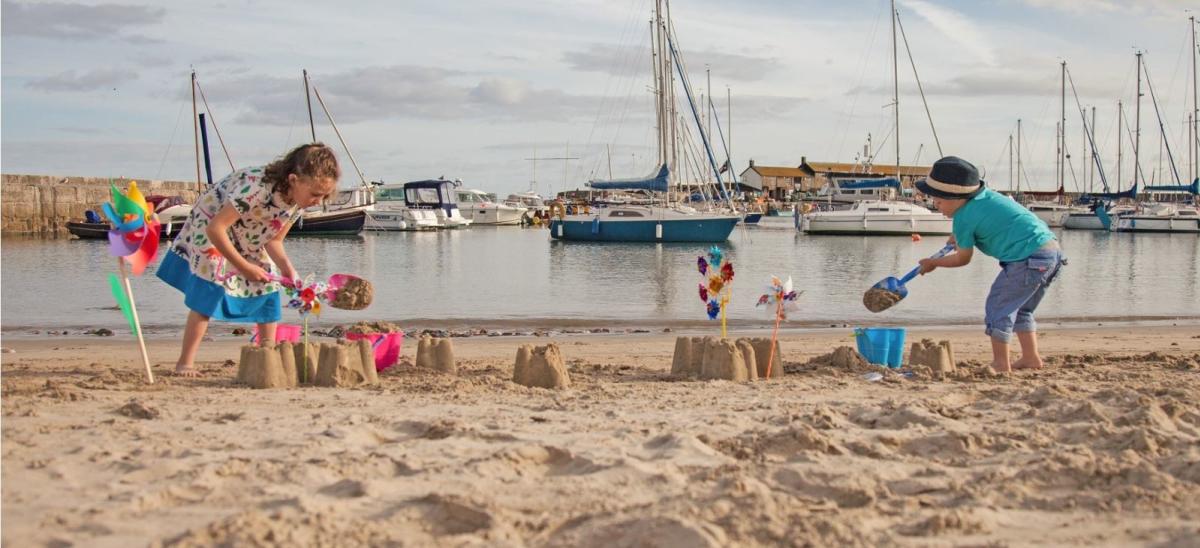 Two children building sand castles on Lyme Regis beach in Dorset