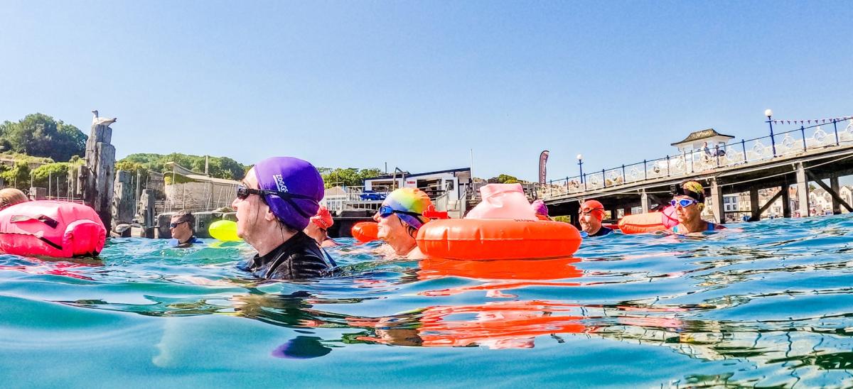 People swimming in the sea near Swanage Pier in Dorset