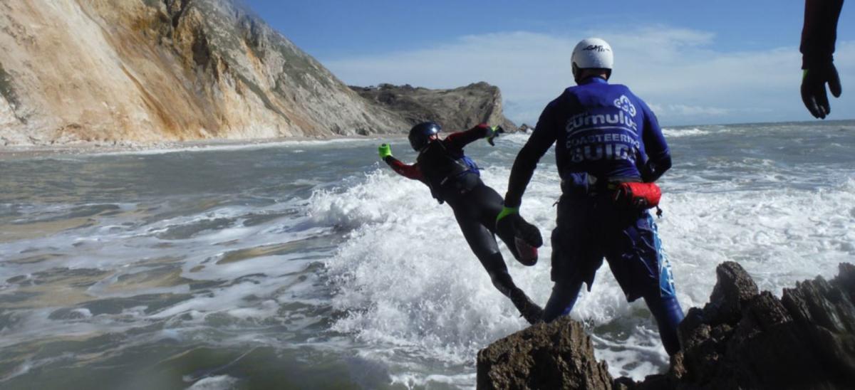 People jumping off rocks, coasteering on the Jurassic Coast in Dorset