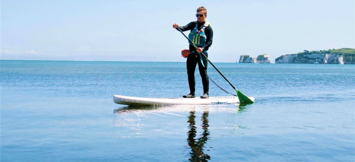 Man stand up paddleboarding at Old Harry Rocks with Fore Adventure